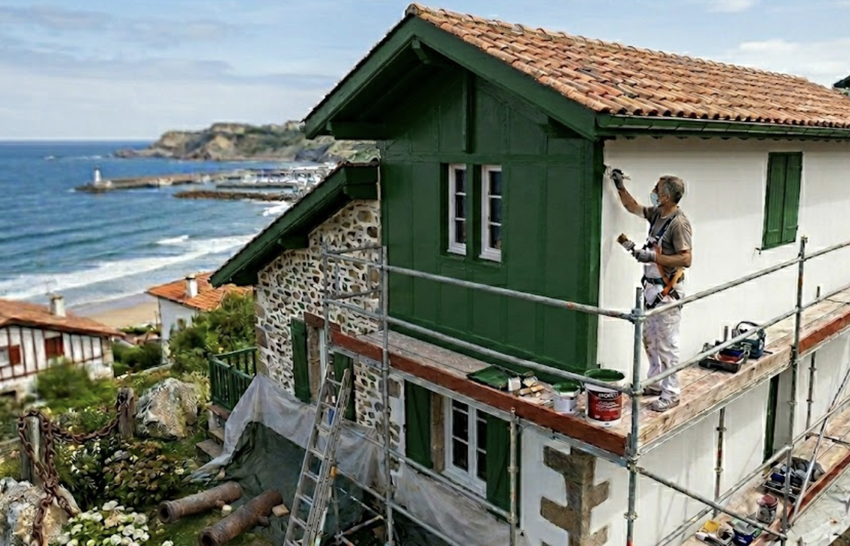 Application d'une peinture microporeuse Rouge Basque sur les colombages et boiseries extérieurs d'une maison